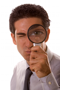 Man holding a magnifying glass over his eye